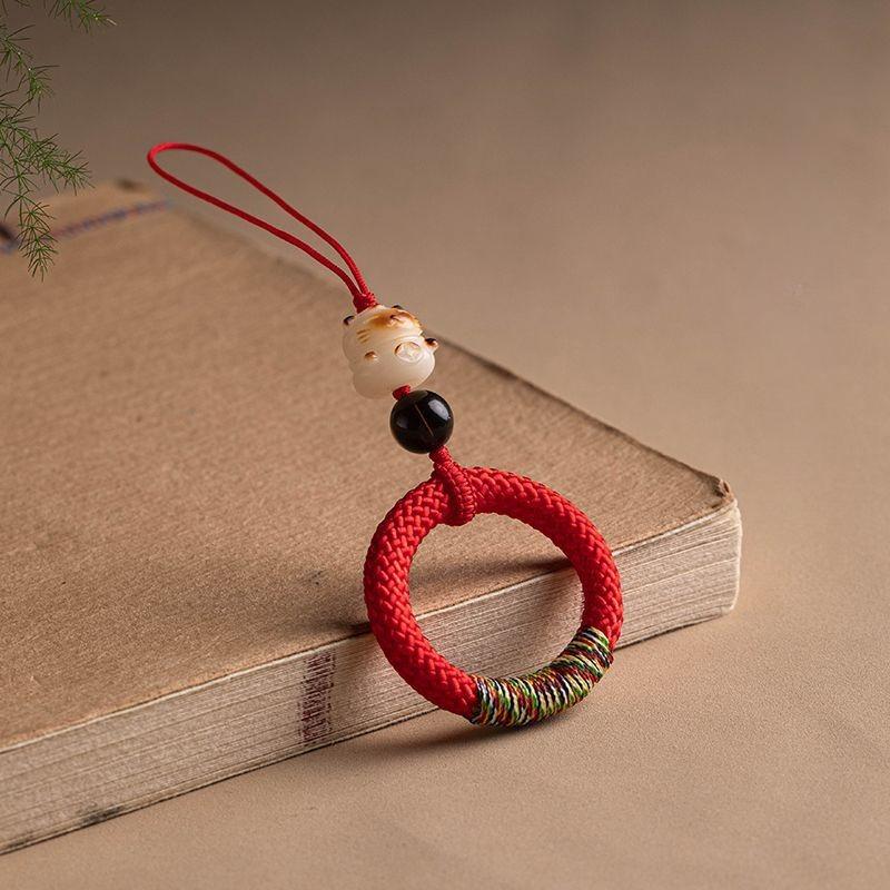 Y290 lucky cat handwoven phone ring strap in dark green held with a smartphone